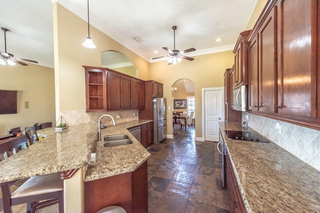 kitchen with sink, a breakfast bar, stainless steel appliances, decorative light fixtures, and kitchen peninsula