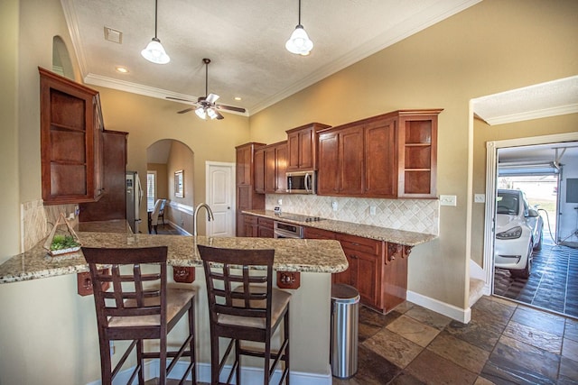 kitchen with a breakfast bar, decorative backsplash, hanging light fixtures, ceiling fan, and kitchen peninsula