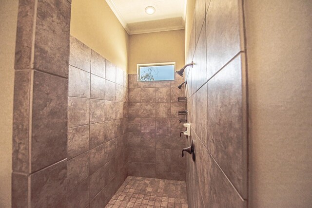 bathroom with ornamental molding and a tile shower