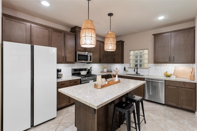 kitchen featuring pendant lighting, sink, backsplash, stainless steel appliances, and a kitchen island