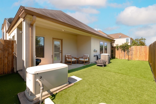 rear view of house with a fenced backyard, stucco siding, a lawn, and central AC