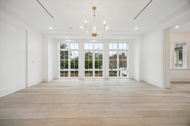 empty room with an inviting chandelier, light hardwood / wood-style flooring, and a wealth of natural light