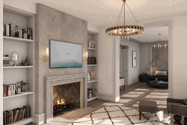 living room with an inviting chandelier, wood-type flooring, a fireplace, and built in features