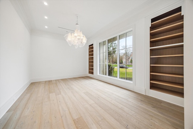 unfurnished room featuring an inviting chandelier, hardwood / wood-style floors, crown molding, and built in shelves