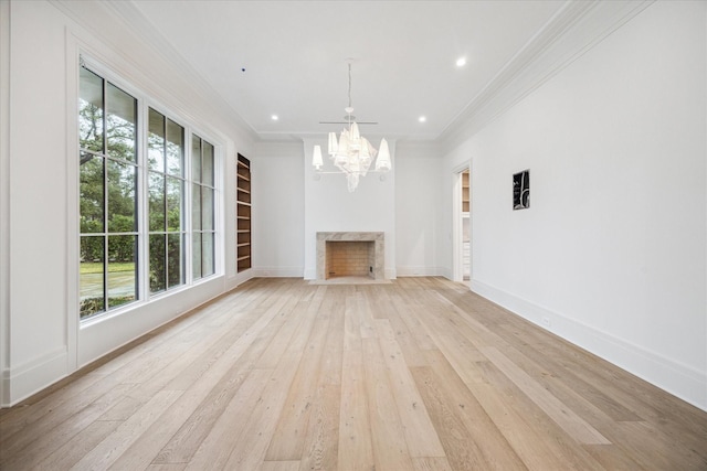 unfurnished living room featuring a chandelier, ornamental molding, built in features, a high end fireplace, and light hardwood / wood-style floors