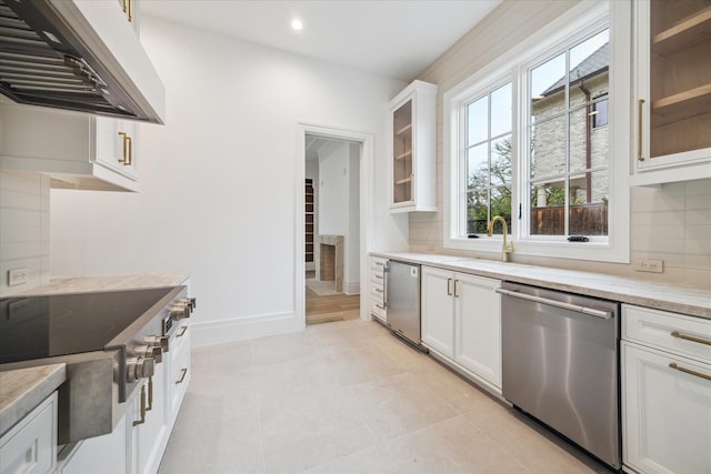 kitchen featuring light stone countertops, range hood, white cabinets, and stainless steel appliances