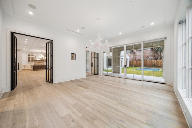 unfurnished living room featuring a chandelier and light wood-type flooring