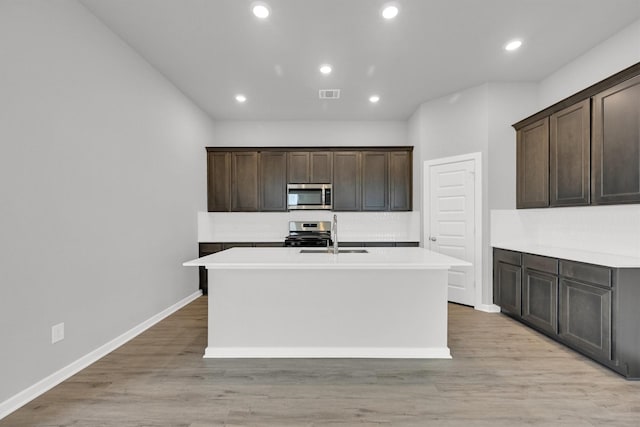 kitchen featuring visible vents, light countertops, an island with sink, appliances with stainless steel finishes, and light wood-style floors