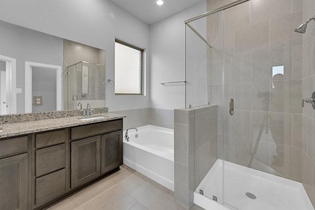 bathroom featuring tile patterned flooring, a stall shower, vanity, and a garden tub