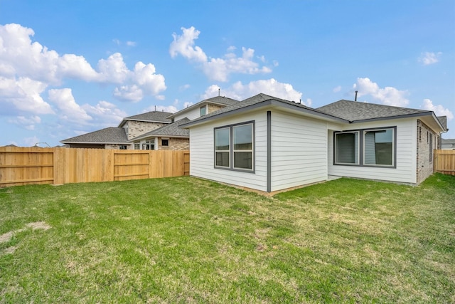 back of house featuring a yard and a fenced backyard