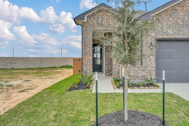 property entrance with brick siding, a garage, and a yard