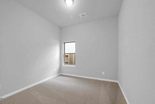 carpeted spare room featuring visible vents and baseboards