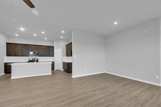 kitchen featuring open floor plan, light wood-style flooring, stainless steel appliances, and baseboards