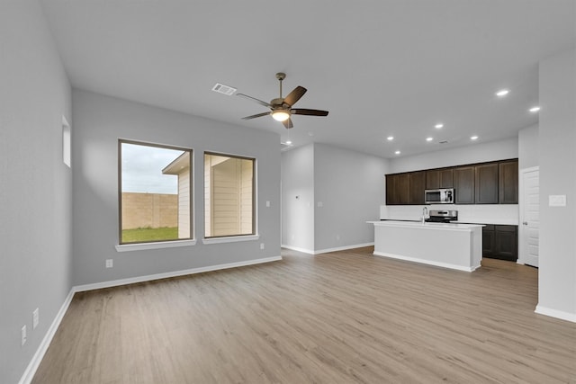 unfurnished living room with ceiling fan, visible vents, baseboards, and light wood-style flooring