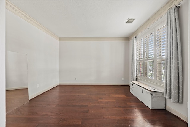 spare room featuring baseboards, dark wood finished floors, visible vents, and crown molding