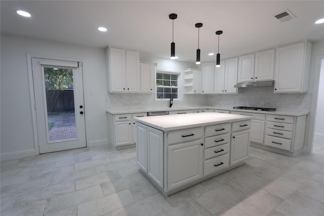 kitchen featuring gas cooktop, tasteful backsplash, white cabinets, a kitchen island, and decorative light fixtures