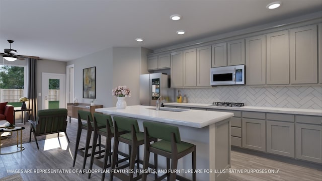 kitchen with a sink, decorative backsplash, appliances with stainless steel finishes, and gray cabinetry