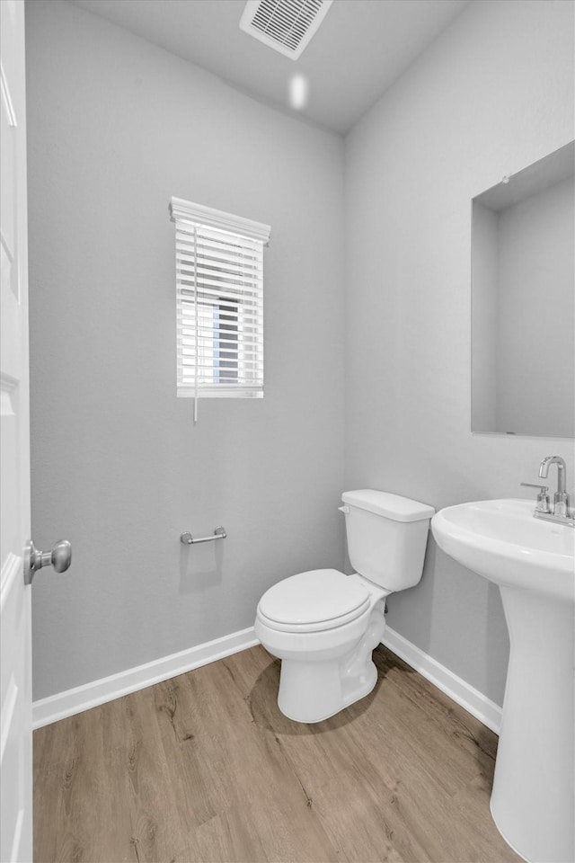 bathroom featuring toilet, wood finished floors, visible vents, and baseboards