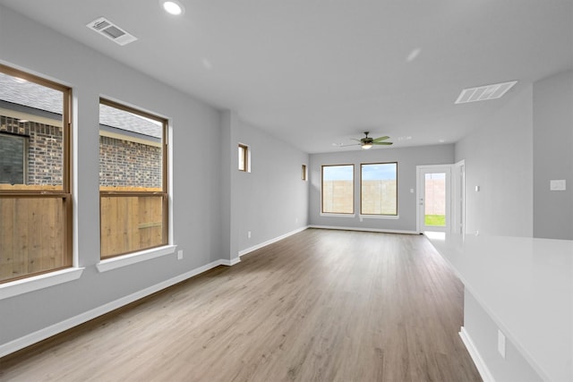 interior space with ceiling fan, visible vents, baseboards, and wood finished floors