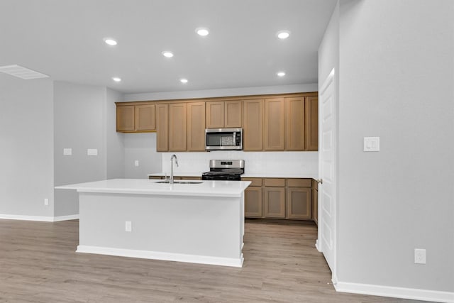 kitchen with light wood finished floors, recessed lighting, brown cabinets, stainless steel appliances, and a sink