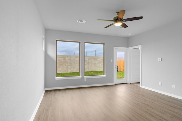 unfurnished room featuring visible vents, wood finished floors, and baseboards