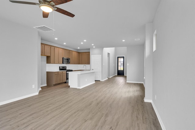 kitchen featuring visible vents, open floor plan, appliances with stainless steel finishes, light wood-style floors, and a sink