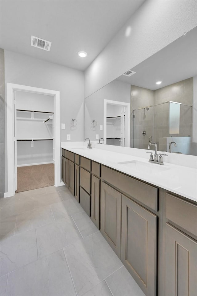 full bathroom featuring double vanity, visible vents, a shower stall, and a sink