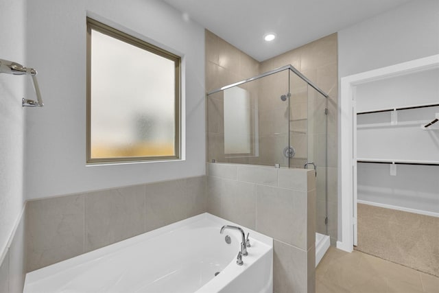 full bathroom with a spacious closet, a shower stall, recessed lighting, a bath, and tile patterned floors