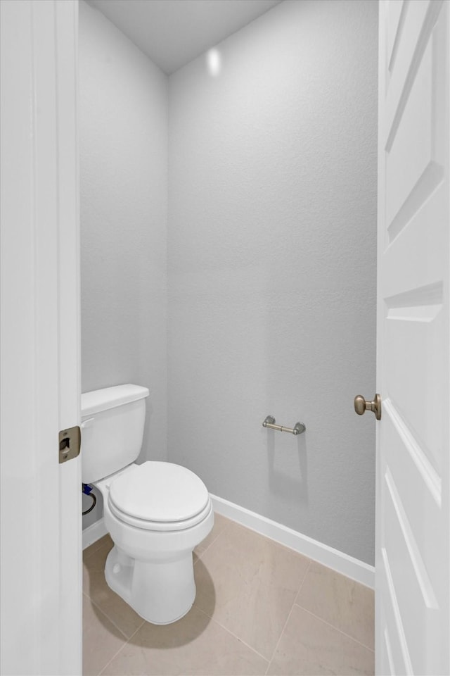 bathroom with baseboards, toilet, and tile patterned flooring