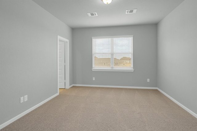 unfurnished room featuring visible vents, baseboards, and light colored carpet