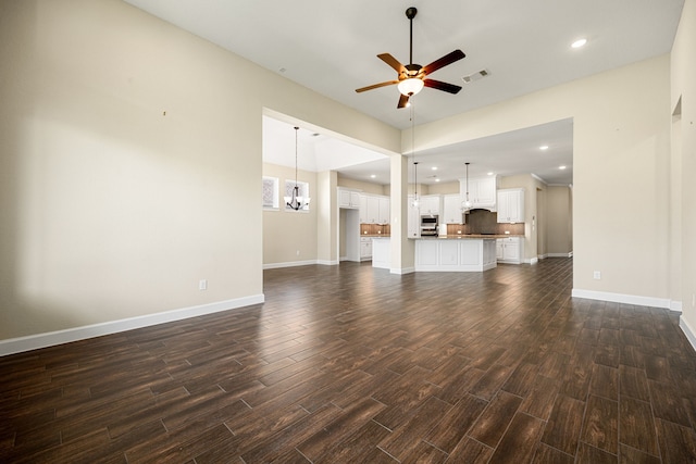 unfurnished living room with visible vents, baseboards, dark wood-style flooring, ceiling fan with notable chandelier, and recessed lighting