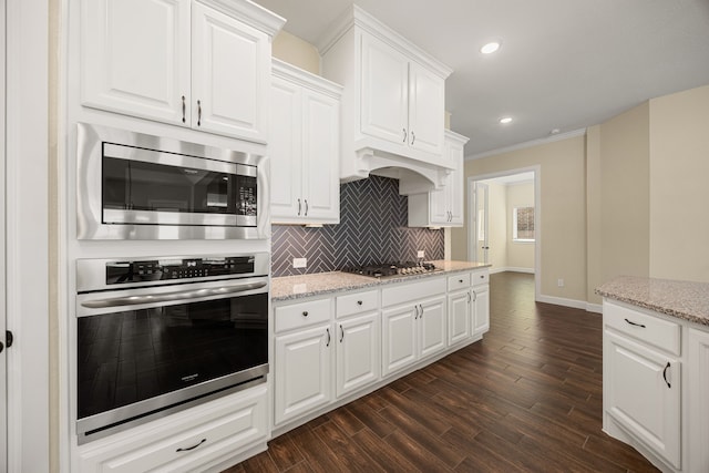 kitchen with stainless steel appliances, dark wood-style flooring, white cabinetry, and decorative backsplash