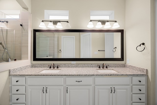 bathroom featuring tiled shower, a sink, and double vanity