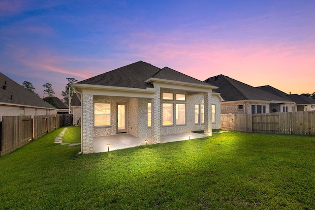 back of house featuring brick siding, a patio, a shingled roof, a lawn, and a fenced backyard