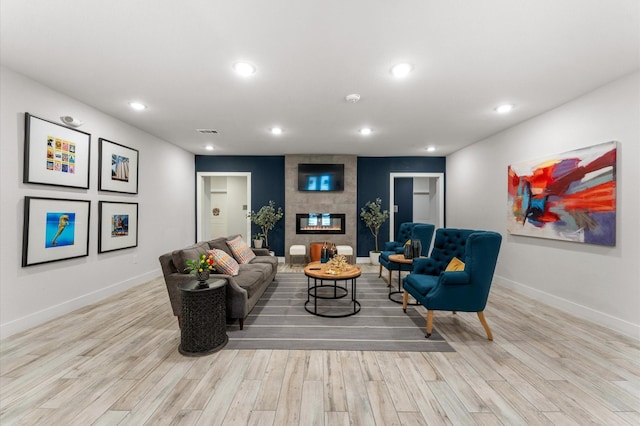 living room featuring light wood-style floors, visible vents, a tiled fireplace, and recessed lighting