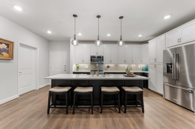 kitchen featuring a kitchen bar, appliances with stainless steel finishes, light countertops, and decorative backsplash