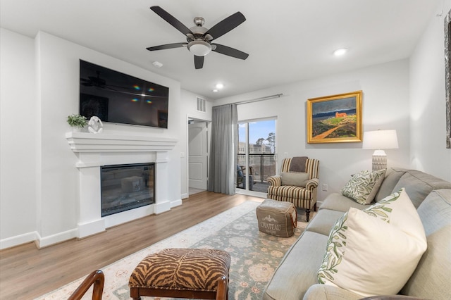 living area featuring recessed lighting, baseboards, wood finished floors, and a glass covered fireplace