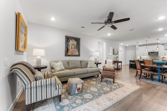 living area with baseboards, wood finished floors, visible vents, and recessed lighting