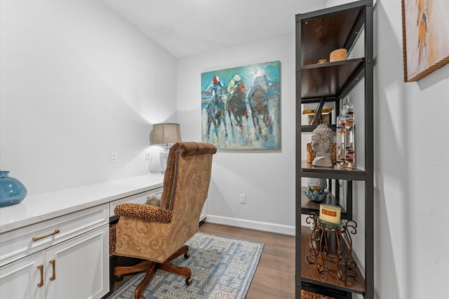 office area featuring wood finished floors, built in study area, and baseboards