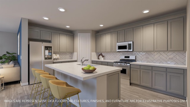 kitchen featuring appliances with stainless steel finishes, a breakfast bar, sink, gray cabinetry, and a kitchen island with sink