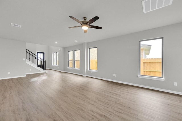 unfurnished living room featuring visible vents, stairs, baseboards, and wood finished floors