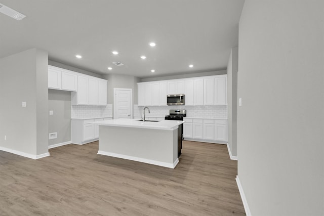 kitchen with a sink, light wood-type flooring, white cabinetry, and stainless steel appliances