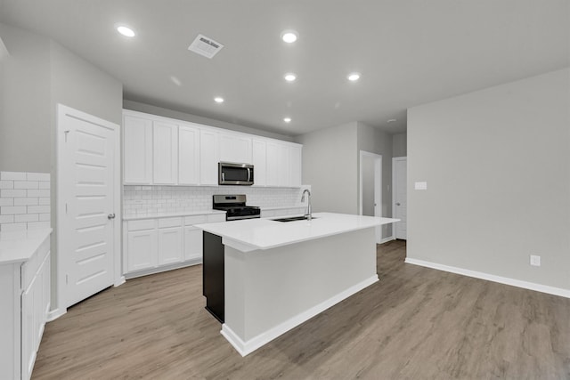 kitchen with visible vents, a sink, light wood-style flooring, stainless steel appliances, and a kitchen island with sink