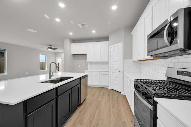 kitchen featuring visible vents, light countertops, white cabinets, stainless steel appliances, and a sink