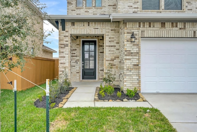 view of exterior entry with a garage, fence, and brick siding