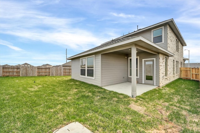 rear view of house with a yard, a patio, brick siding, and a fenced backyard