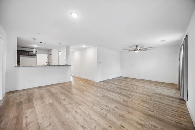 unfurnished living room featuring ceiling fan and light wood-type flooring