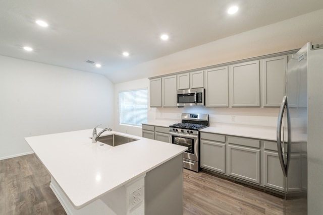 kitchen with appliances with stainless steel finishes, light hardwood / wood-style flooring, an island with sink, gray cabinets, and sink