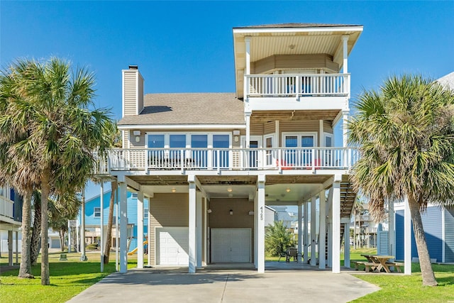 raised beach house featuring a garage, a balcony, and a carport