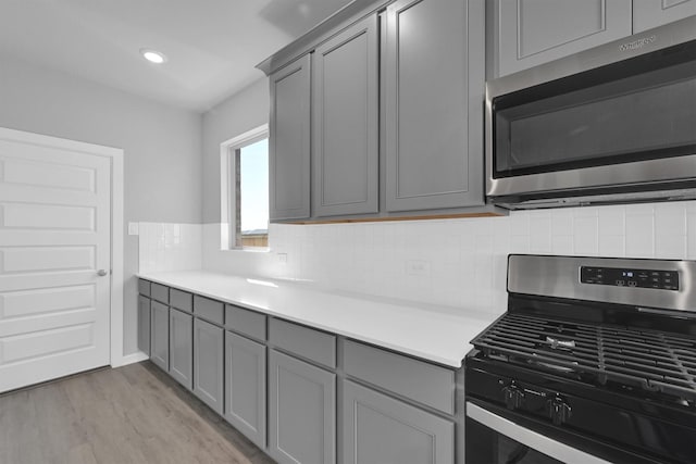 kitchen featuring tasteful backsplash, gray cabinetry, stainless steel appliances, and light countertops